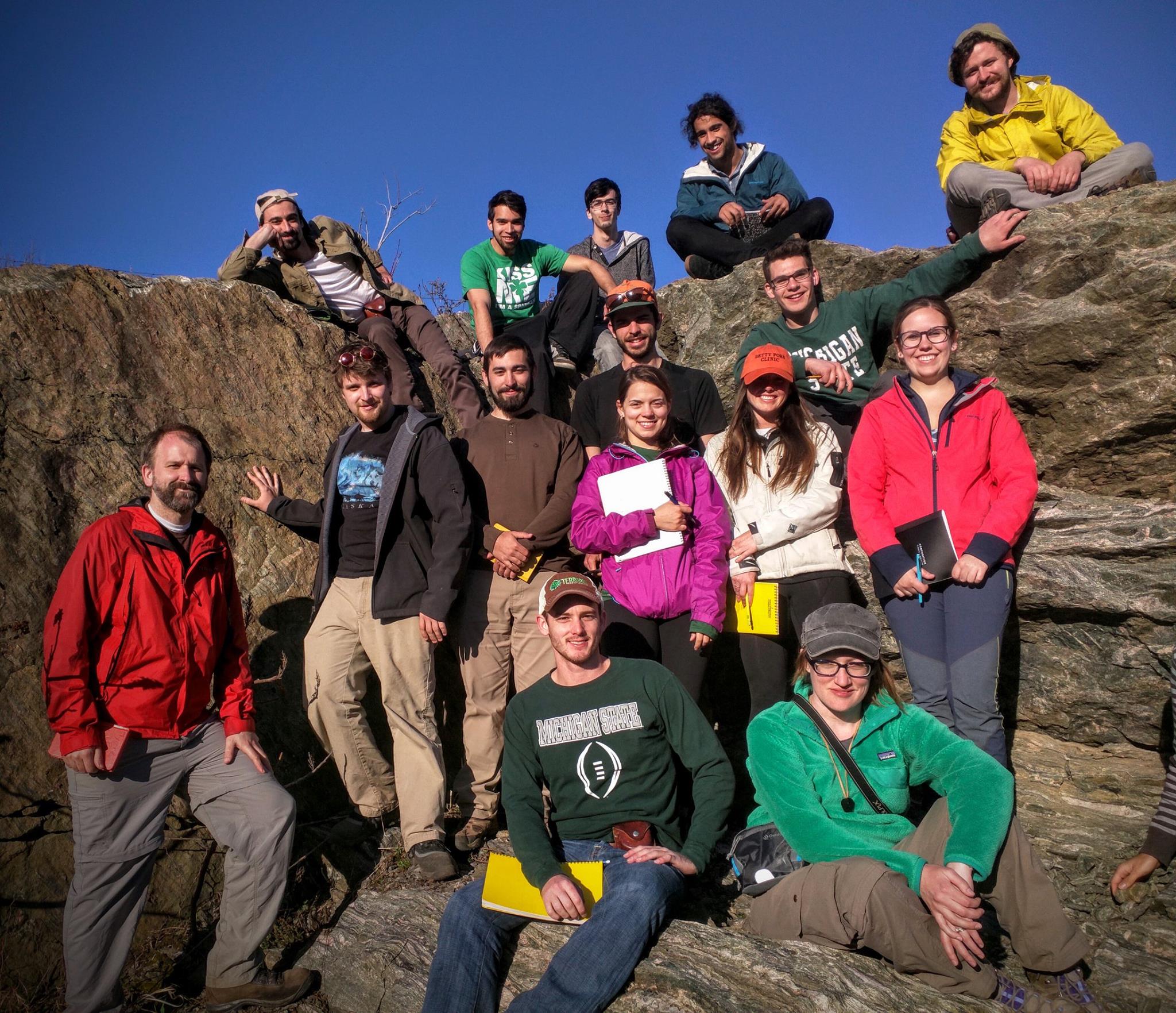 students sitting on a large rock formation